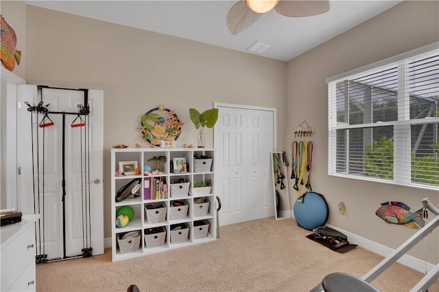 exercise area with light colored carpet and ceiling fan