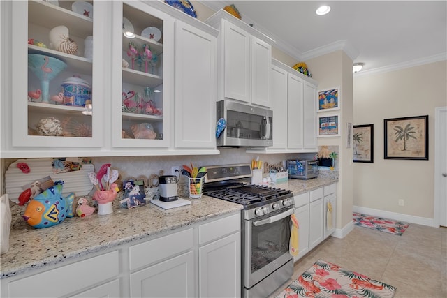 kitchen with stainless steel appliances, white cabinets, light tile patterned floors, crown molding, and backsplash