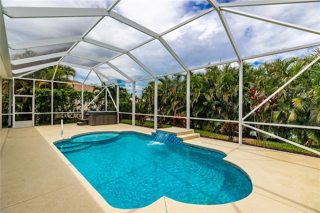 view of swimming pool with a hot tub, glass enclosure, pool water feature, and a patio area