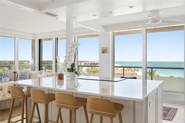 kitchen with a kitchen breakfast bar, ceiling fan, a water view, and a center island