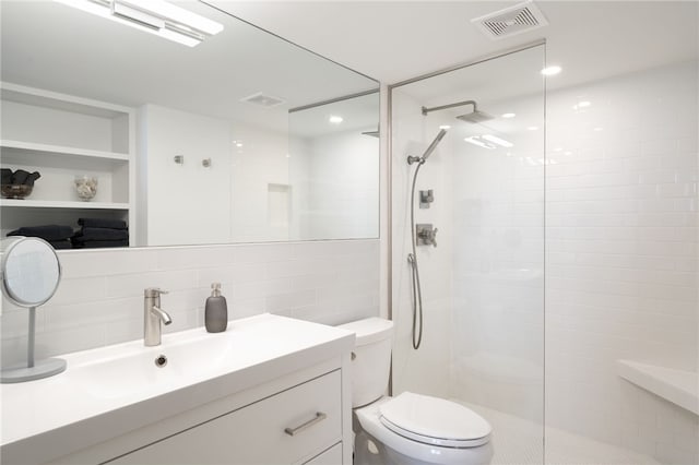 bathroom featuring vanity, decorative backsplash, tile walls, toilet, and tiled shower