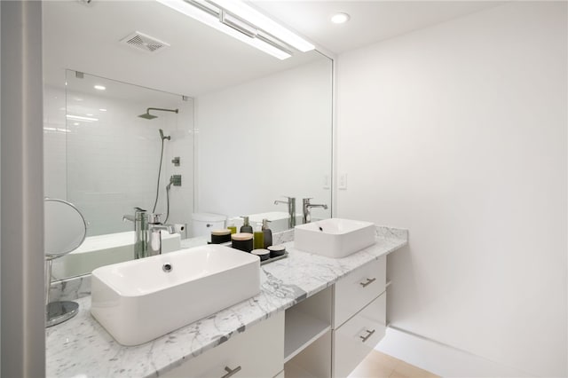 bathroom featuring toilet, vanity, tile patterned flooring, and a tile shower