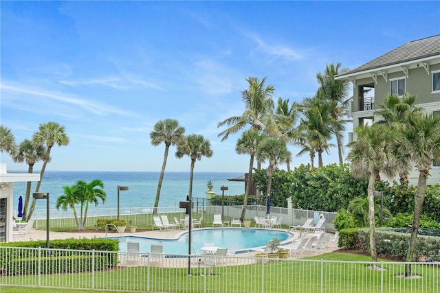 view of pool with a lawn and a water view