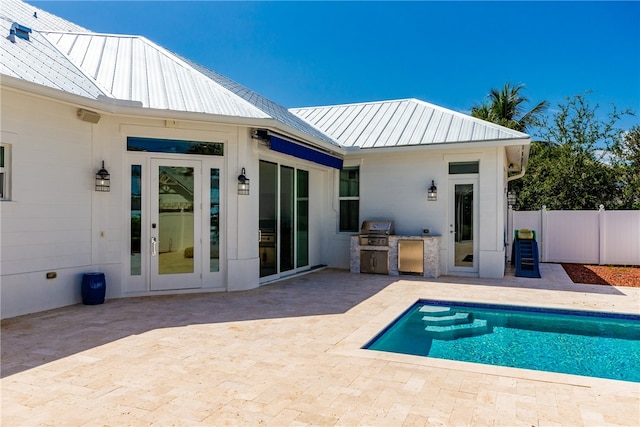 rear view of house with a fenced in pool, a patio area, and exterior kitchen