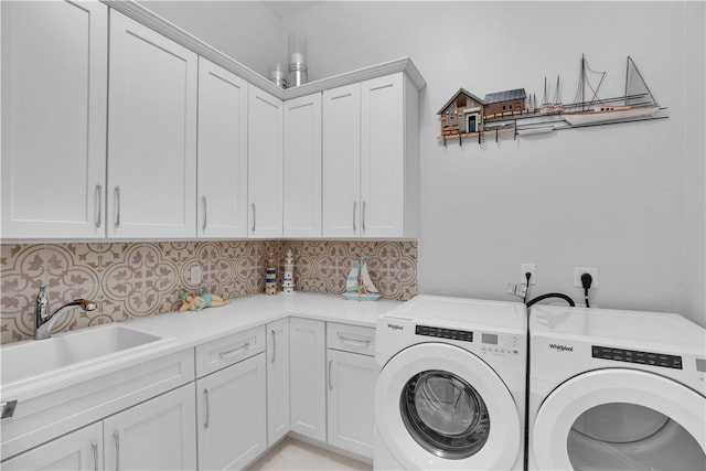 clothes washing area featuring washer and clothes dryer, cabinets, and sink