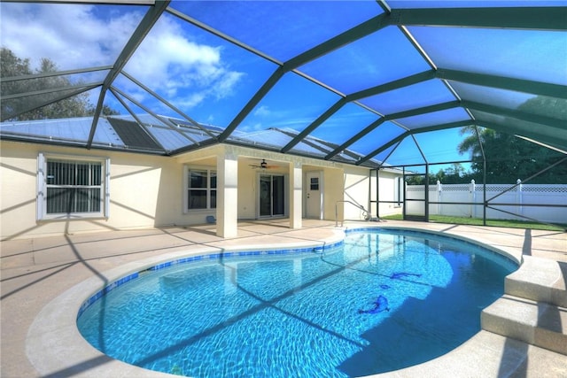 view of swimming pool featuring a patio, glass enclosure, and ceiling fan