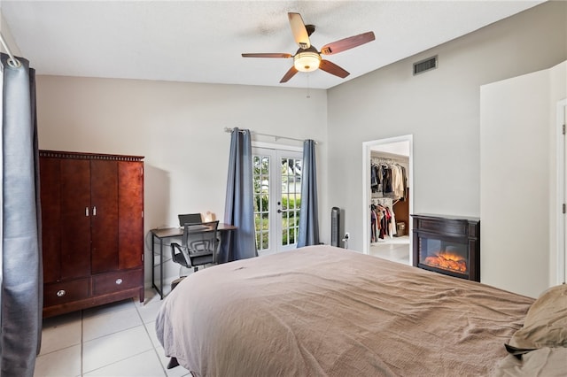 bedroom featuring a walk in closet, vaulted ceiling, ceiling fan, a closet, and light tile patterned flooring