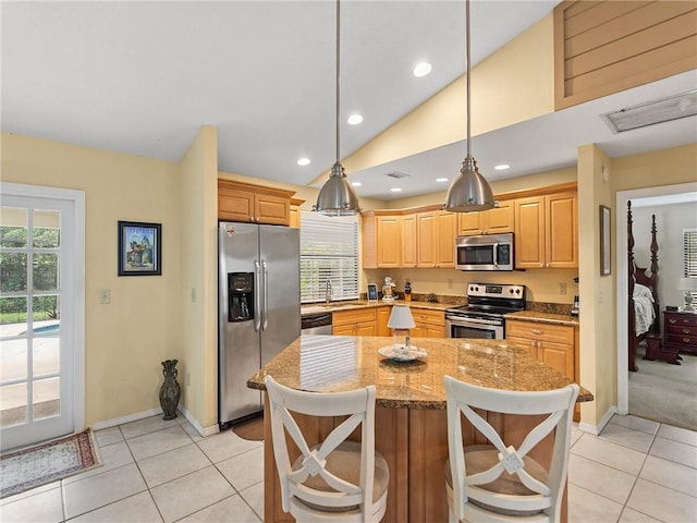 kitchen with light stone countertops, appliances with stainless steel finishes, vaulted ceiling, light tile patterned floors, and a center island