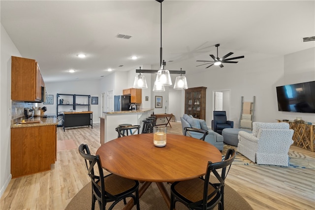 dining space with light wood-type flooring, lofted ceiling, and ceiling fan