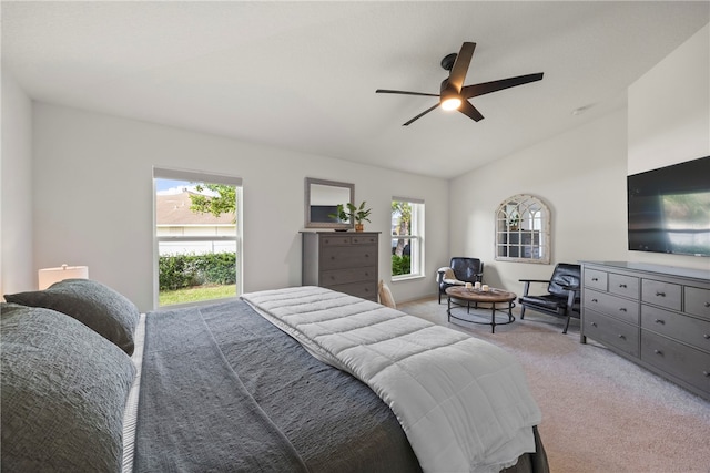 bedroom featuring multiple windows, vaulted ceiling, light carpet, and ceiling fan