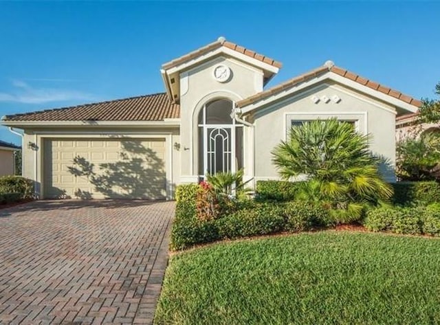 mediterranean / spanish home featuring a front yard and a garage