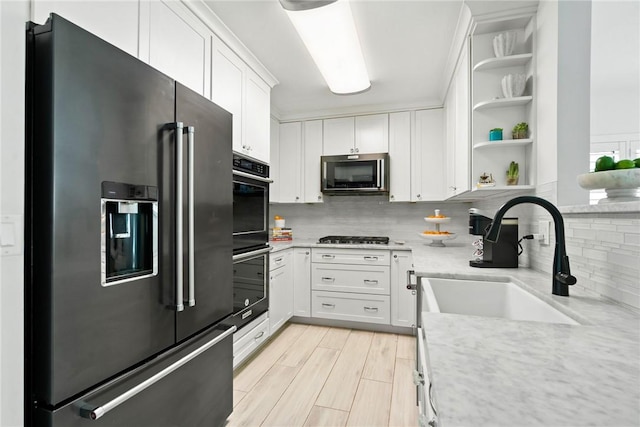 kitchen featuring white cabinetry, high end refrigerator, sink, and light stone counters