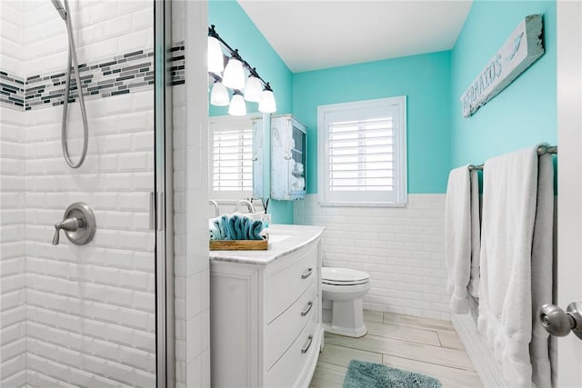 bathroom with tile walls, vanity, toilet, and an enclosed shower