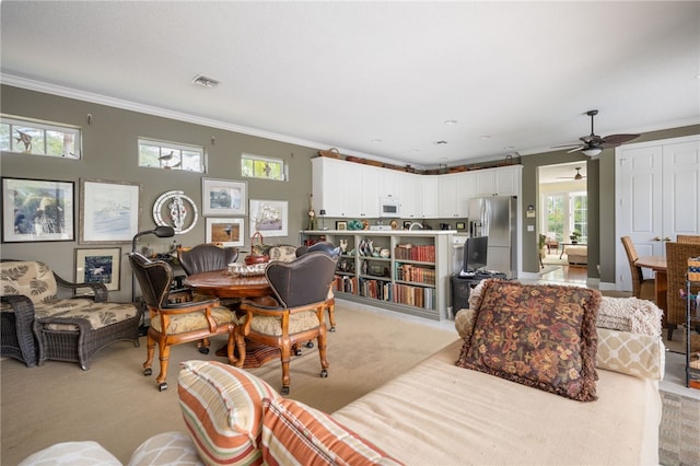 carpeted living room featuring ceiling fan, ornamental molding, and plenty of natural light