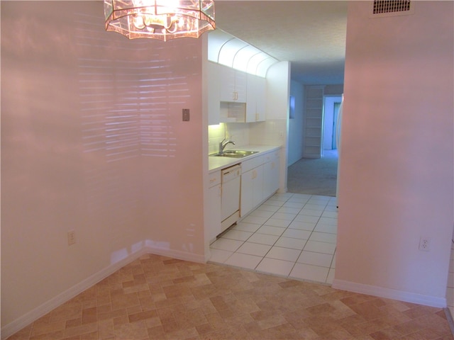 kitchen with backsplash, light tile patterned floors, white dishwasher, sink, and white cabinets