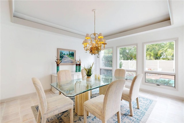 dining area with baseboards, a tray ceiling, and a notable chandelier