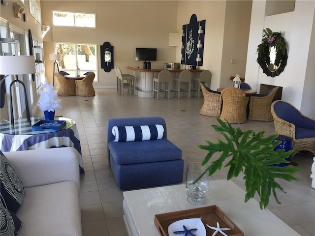 living area with a towering ceiling, tile patterned flooring, and baseboards