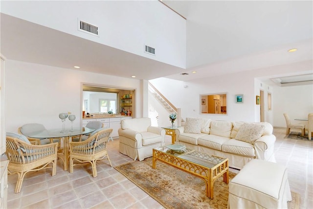 living area with a high ceiling, visible vents, and recessed lighting