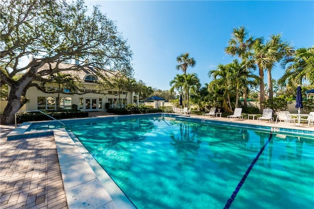 pool with french doors, a patio, and fence