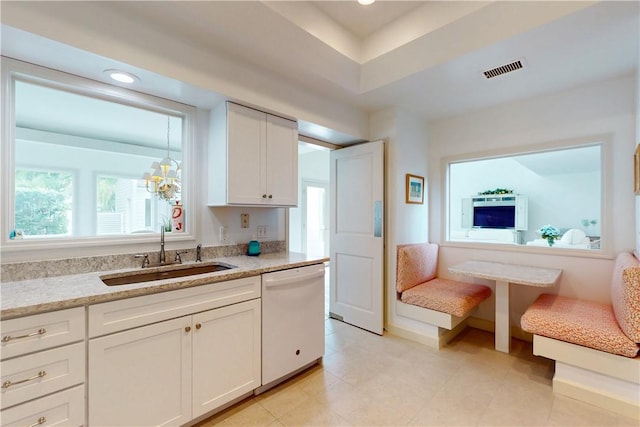 kitchen featuring visible vents, dishwasher, light stone counters, white cabinetry, and a sink