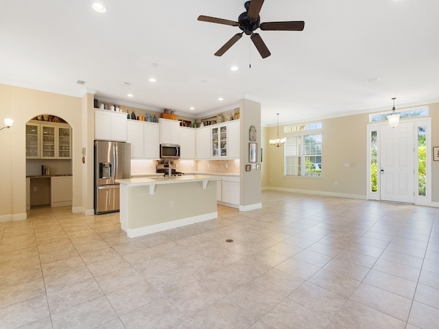 kitchen with stainless steel appliances, a center island with sink, crown molding, backsplash, and pendant lighting