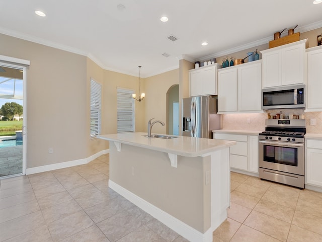 kitchen with stainless steel appliances, white cabinetry, tasteful backsplash, a kitchen island with sink, and pendant lighting