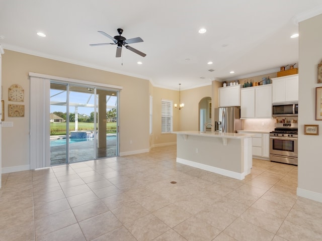 kitchen featuring white cabinets, appliances with stainless steel finishes, ornamental molding, and a center island with sink