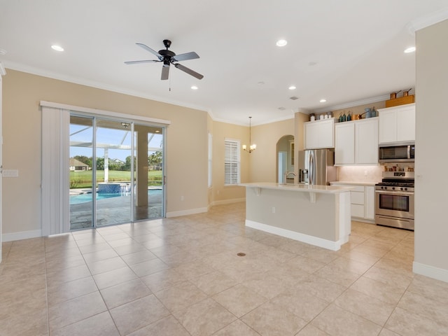 kitchen featuring a kitchen island with sink, white cabinetry, stainless steel appliances, and ornamental molding