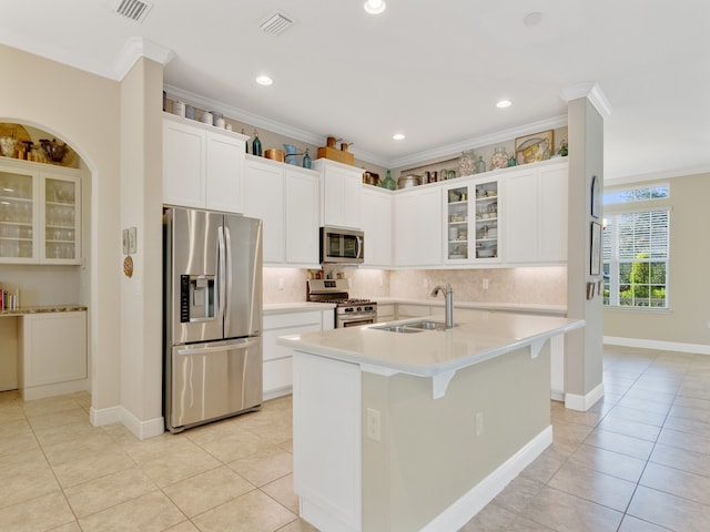 kitchen featuring a kitchen island with sink, stainless steel appliances, ornamental molding, and sink