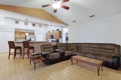 living room with ceiling fan, high vaulted ceiling, and light hardwood / wood-style flooring