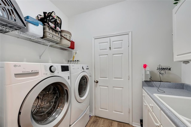 laundry room featuring washer and dryer, light hardwood / wood-style flooring, cabinets, and sink