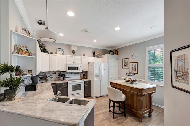 kitchen featuring white appliances, crown molding, decorative light fixtures, light hardwood / wood-style floors, and white cabinetry