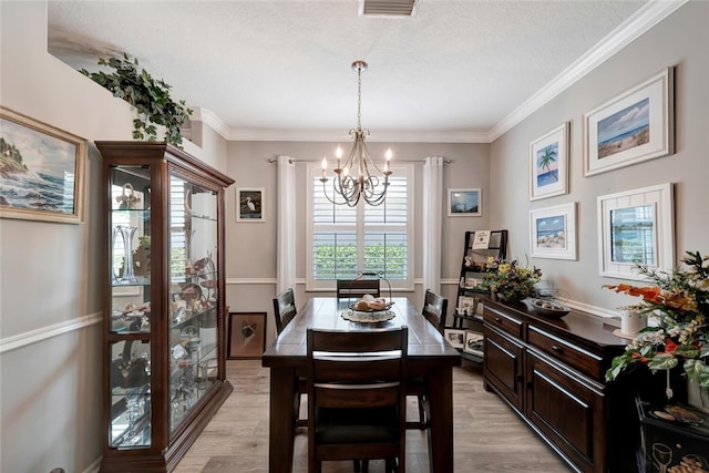 dining area featuring light hardwood / wood-style flooring, an inviting chandelier, and crown molding