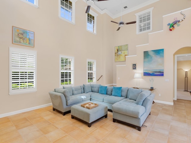 living room with light tile patterned flooring, a high ceiling, ceiling fan, and crown molding