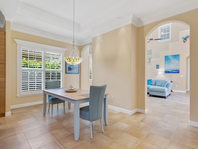 tiled dining area with ceiling fan with notable chandelier, a raised ceiling, and crown molding