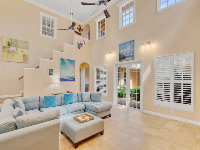 living room with ornamental molding, a towering ceiling, ceiling fan, and french doors