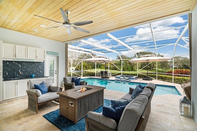 view of swimming pool with an in ground hot tub, an outdoor living space with a fire pit, glass enclosure, and a patio area