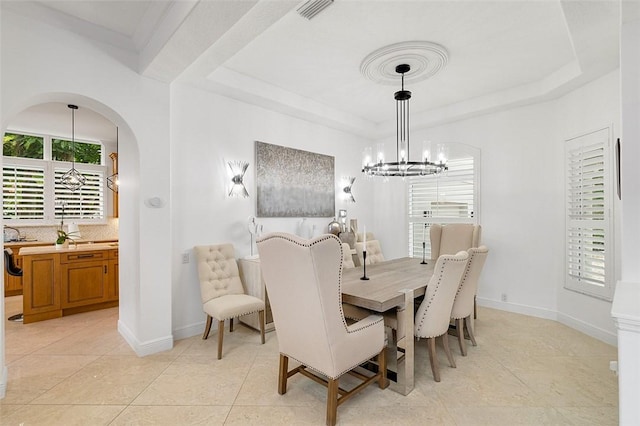 dining area with light tile patterned flooring, a healthy amount of sunlight, an inviting chandelier, and a tray ceiling