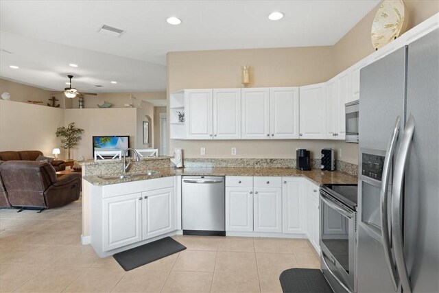 kitchen with sink, light tile patterned floors, appliances with stainless steel finishes, white cabinets, and kitchen peninsula