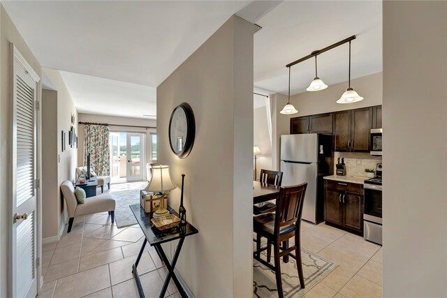 kitchen with dark brown cabinetry, stainless steel appliances, hanging light fixtures, and light tile patterned flooring