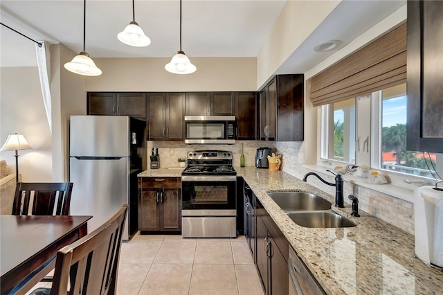 kitchen with sink, tasteful backsplash, light stone countertops, pendant lighting, and appliances with stainless steel finishes