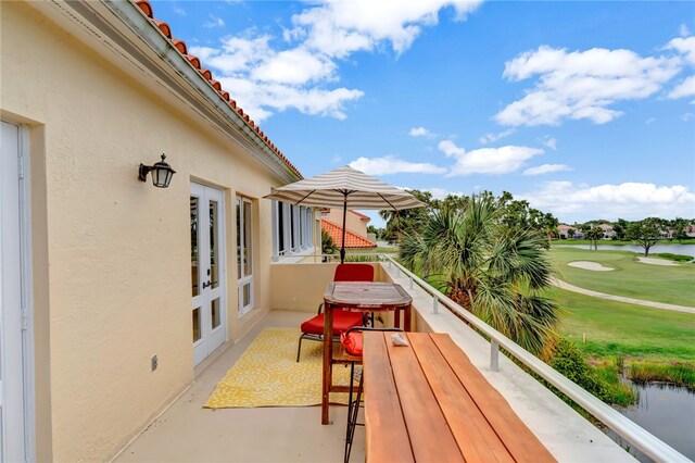 view of patio / terrace featuring french doors, a water view, and a balcony