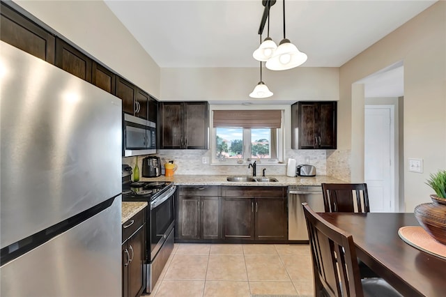 kitchen with dark brown cabinetry, hanging light fixtures, sink, light stone countertops, and appliances with stainless steel finishes