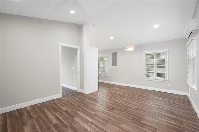 spare room featuring electric panel, a wall unit AC, dark hardwood / wood-style floors, and ceiling fan