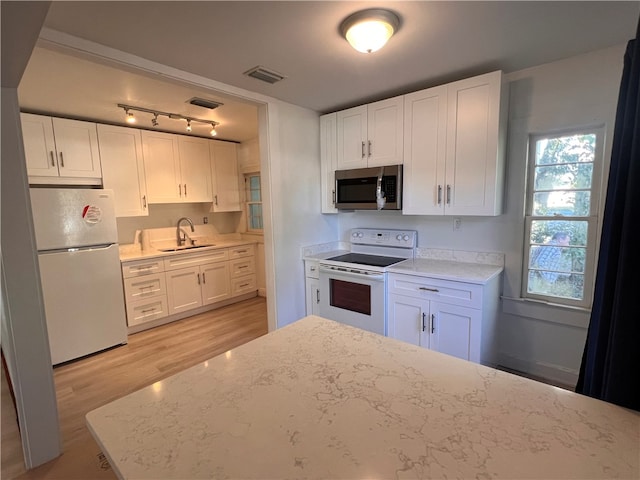 kitchen with sink, light stone counters, white appliances, light hardwood / wood-style flooring, and white cabinets