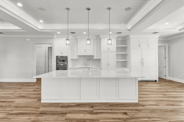 kitchen featuring a spacious island, pendant lighting, a raised ceiling, and white cabinets