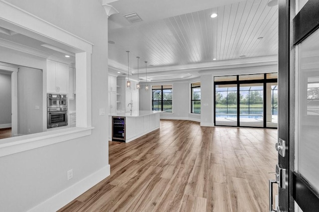 unfurnished living room with wine cooler, wood ceiling, ornamental molding, and light wood-type flooring