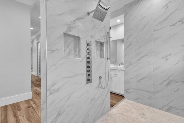 bathroom featuring wood-type flooring, tiled shower, and vanity