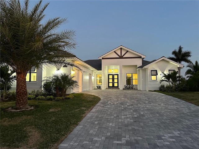 view of front facade with a garage, a lawn, and french doors