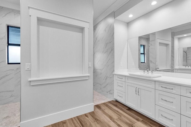 bathroom with hardwood / wood-style flooring, vanity, and a tile shower